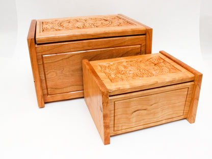 Wooden keepsake boxes with hinged lids engraved with a floral design and available in two sizes.